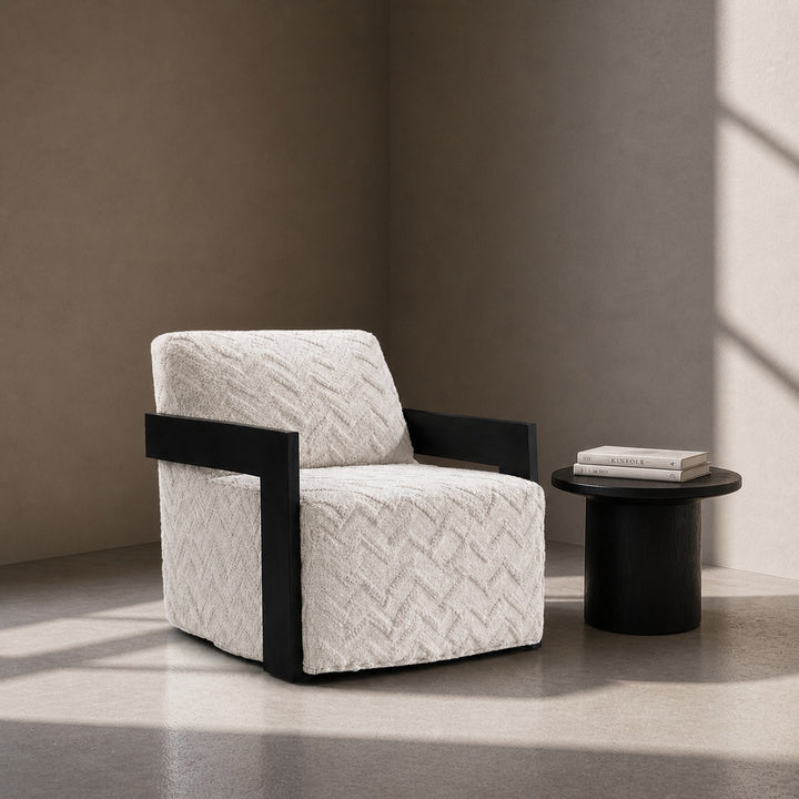 Modern armchair with black frame and textured white cushion in a minimalistic room.