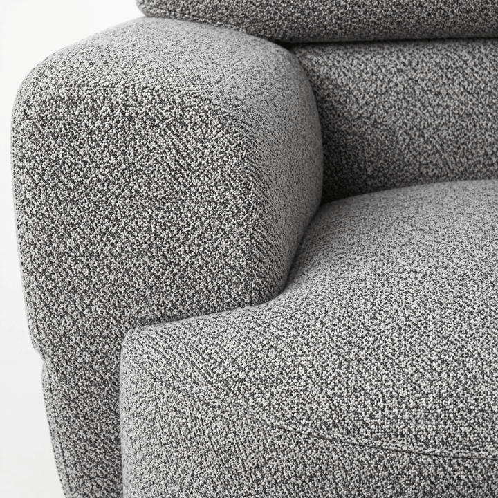 Close-up of a textured gray sofa armrest and backrest.