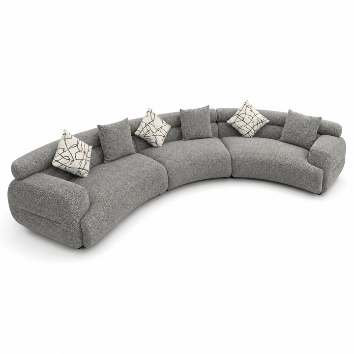 Gray curved sectional sofa with patterned cushions on a white background