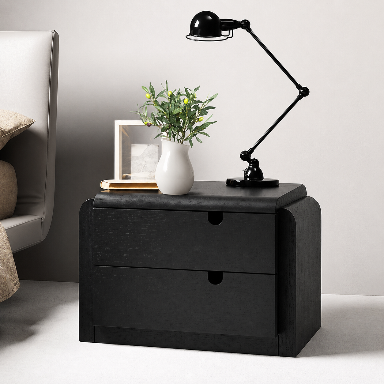Black nightstand with a lamp, plant, and framed picture in a bedroom setting.