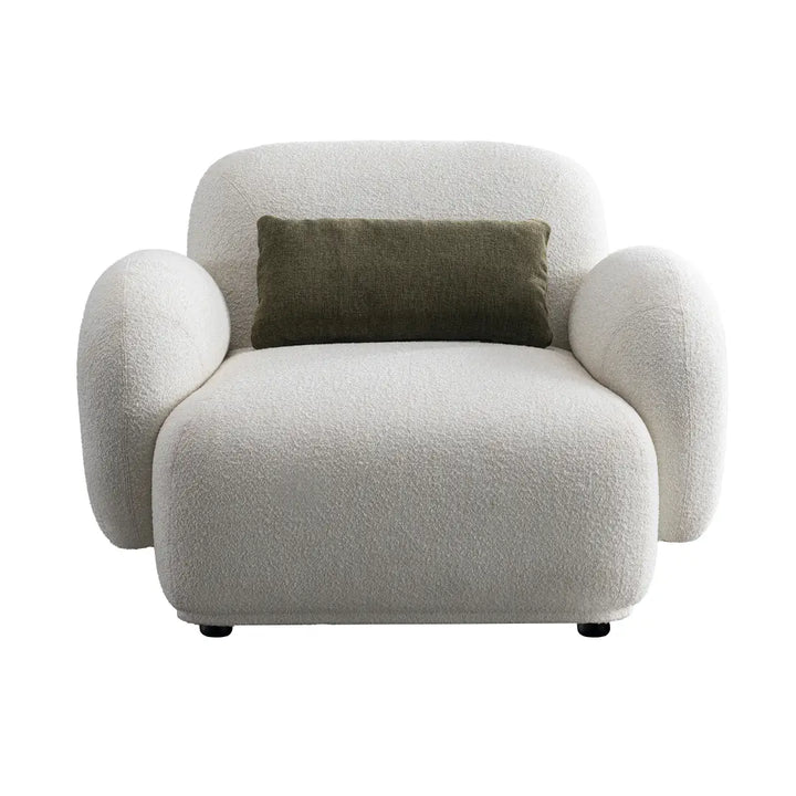 Modern armchair with a textured surface and a green pillow on a white background