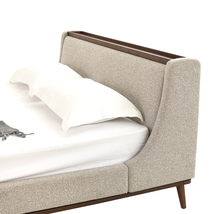 Beige upholstered bed with wooden frame on a white background