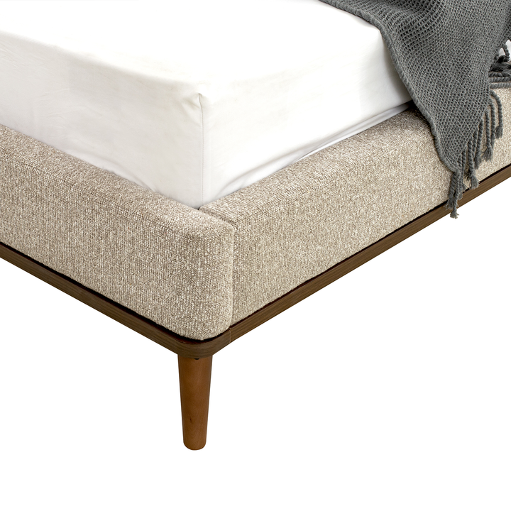 Beige upholstered bed frame with wooden legs on a white background