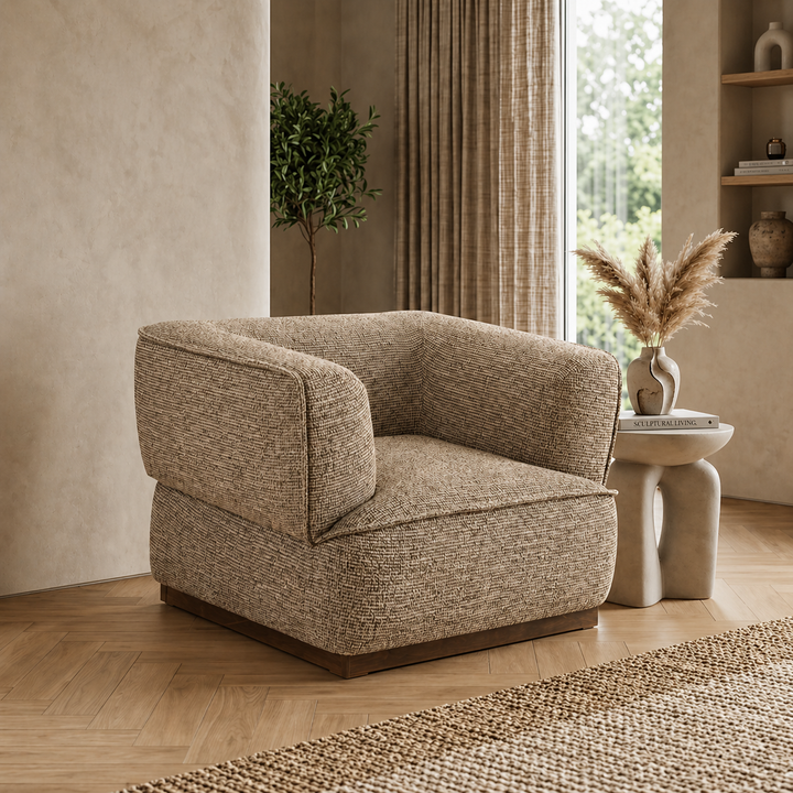 Brown textured armchair in a room with a window, plant, and small table.