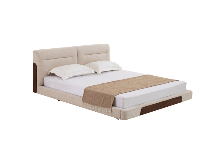 Beige upholstered bed with white bedding and a brown blanket on a white background