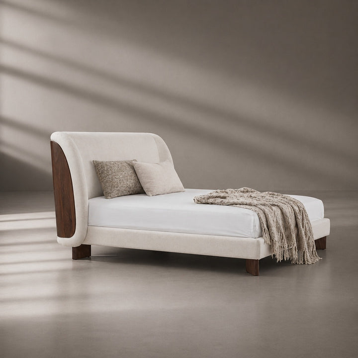 White bed with wooden headboard and brown blanket on a neutral background