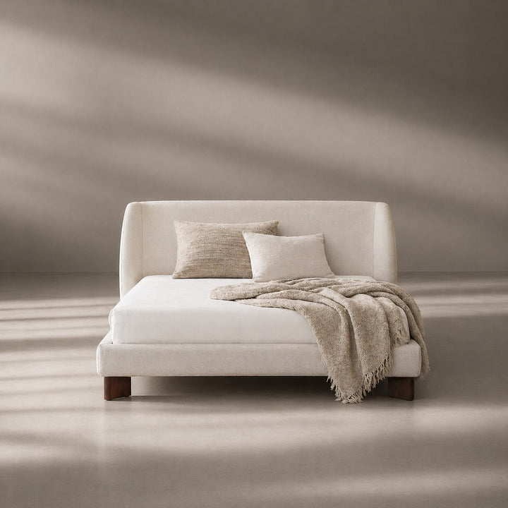 White bed with beige pillows and blanket in a minimalistic room