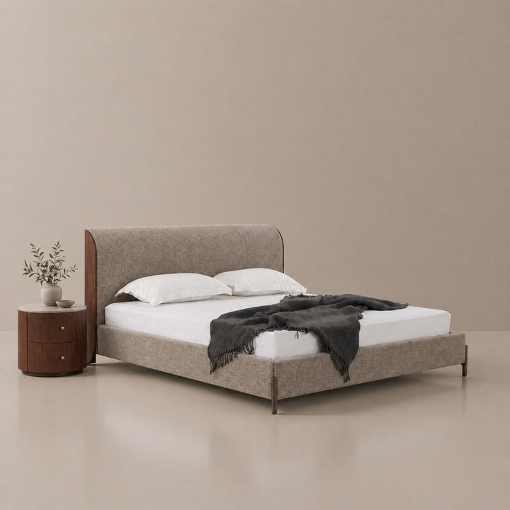 Beige upholstered bed with white bedding and a black throw blanket in a minimalistic room.
