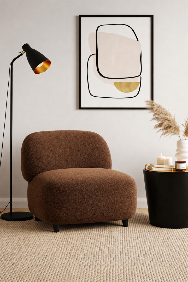 Brown armchair in a room with a black floor lamp, abstract art, and a small table with candles.