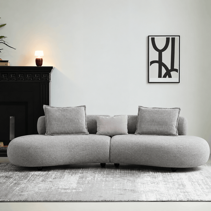 Gray sofa in a living room with a fireplace and abstract art on the wall.