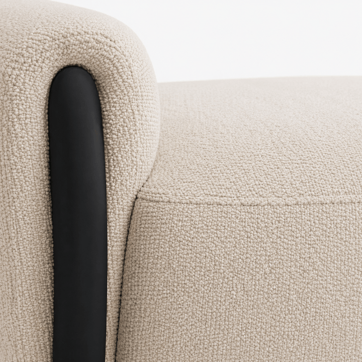 Close-up of a textured beige sofa with a black armrest.