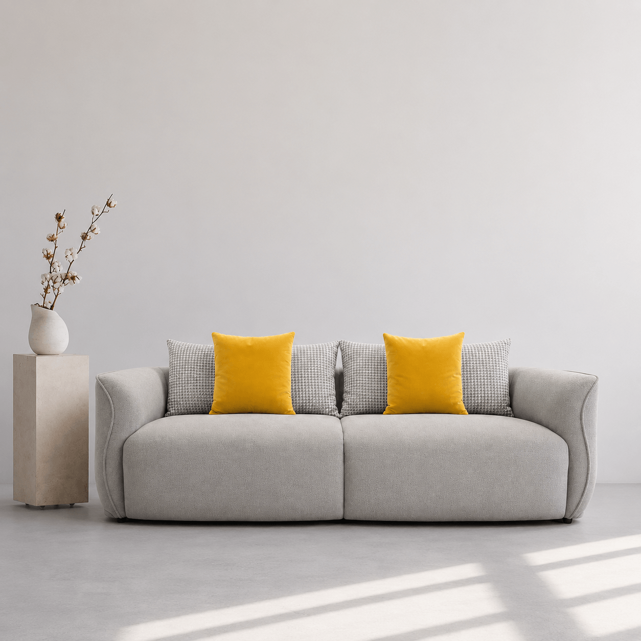 Gray sofa with yellow and patterned cushions in a minimalistic room.