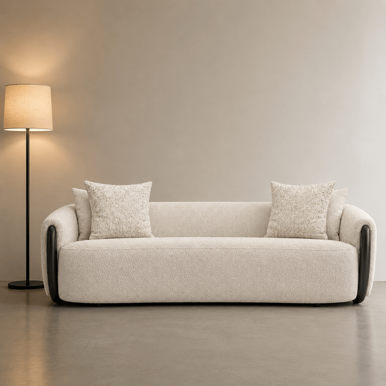 Beige sofa with two cushions in a room with a lamp and neutral walls.