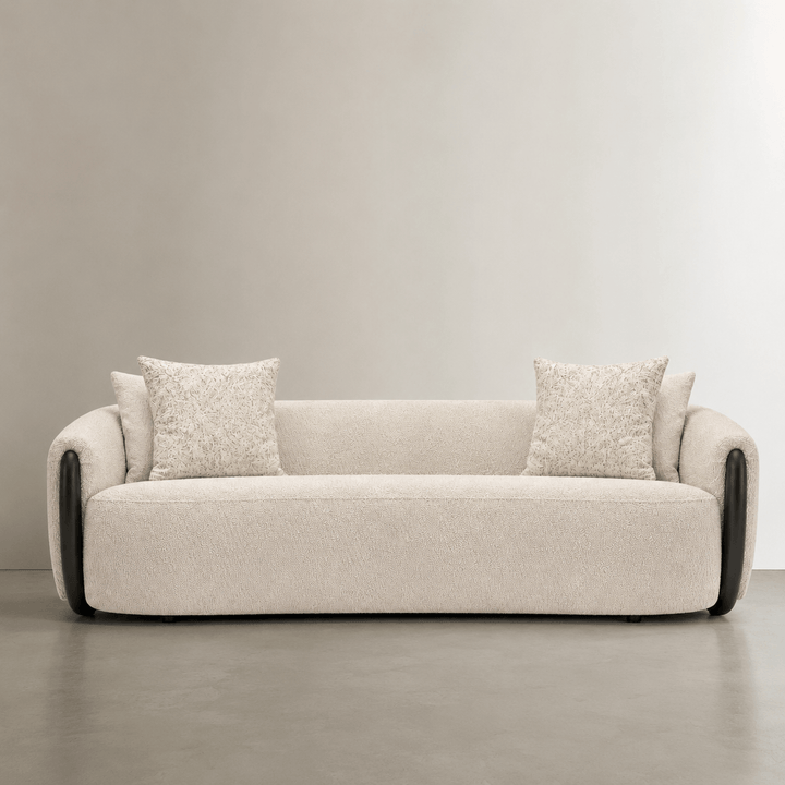 Beige sofa with two cushions on a neutral background