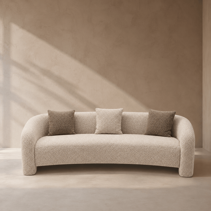 Beige sofa with three cushions in a minimalistic room with soft lighting