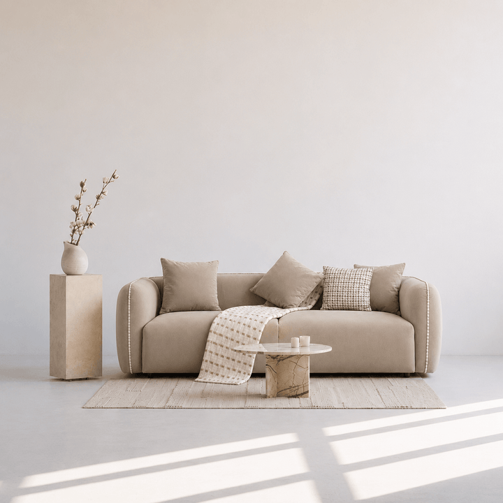 Beige sofa with decorative pillows and a small table in a minimalistic room.