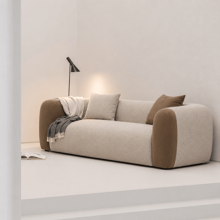 Modern beige sofa with brown accents in a minimalistic room.