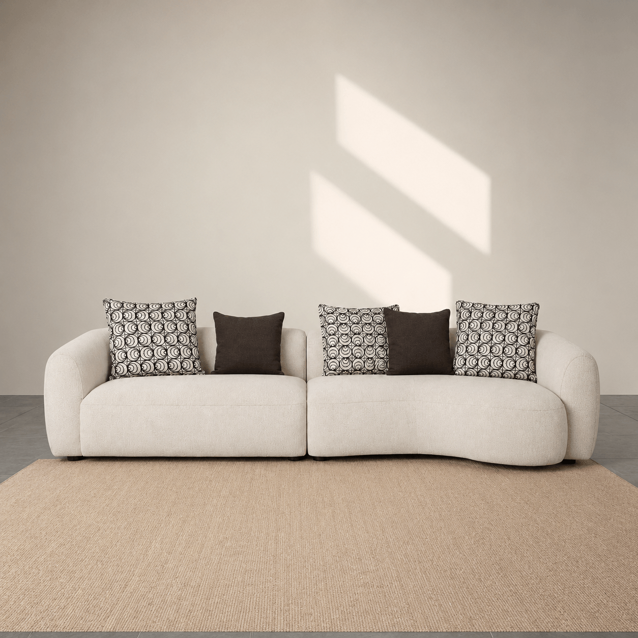 White sofa with patterned cushions in a minimalistic room with sunlight streaming through a window.
