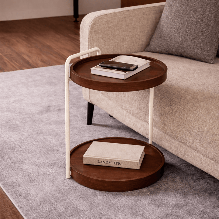 Small round wooden side table with a white metal frame next to a beige sofa.