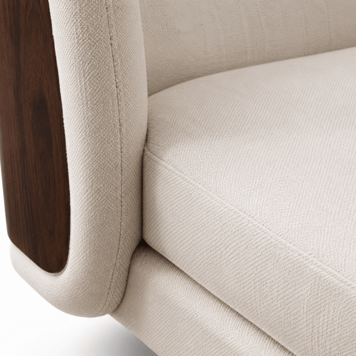 Close-up of a beige upholstered chair with wooden armrest.