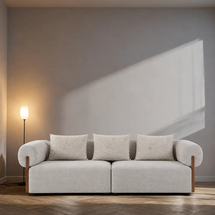 Light gray sofa with wooden legs in a minimalistic room with a lamp and abstract painting.