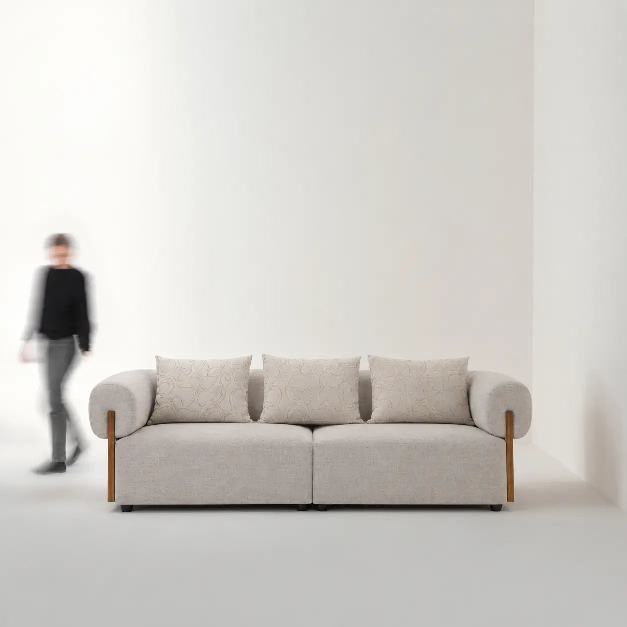 Beige sofa in a minimalistic room with a person in the background