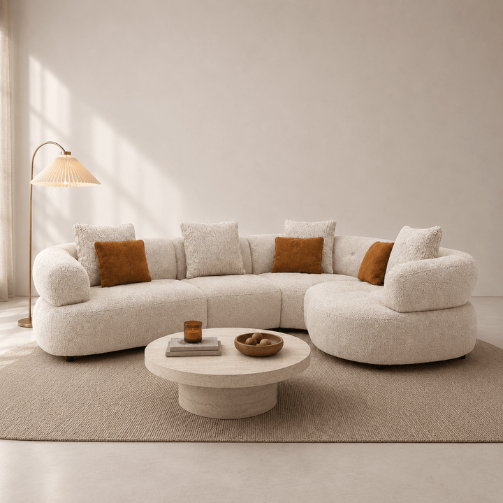 Modern living room with a beige sectional sofa, round coffee table, and decorative pillows.