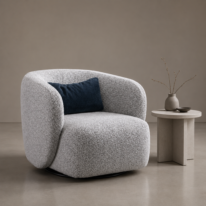 Gray textured armchair with a blue pillow in a minimalistic room.