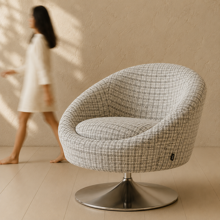 Modern swivel chair with a woman in a white dress walking by in a minimalistic room.