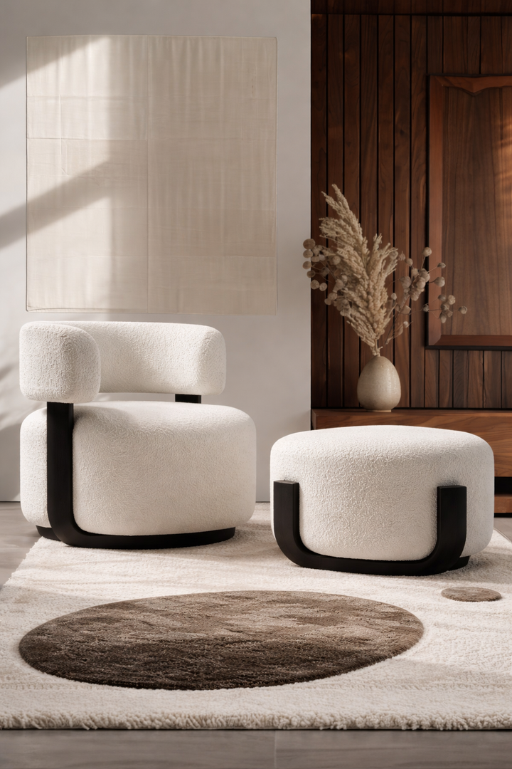 Modern white armchair with black accents and matching ottoman in a room with wooden wall and rug.