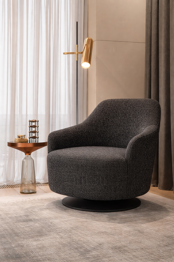 Gray swivel chair in a modern room with curtains and a side table.